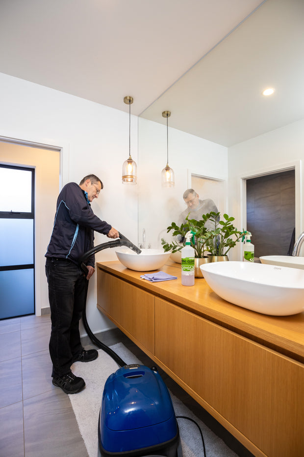Man in cleaning uniform steam cleaning a bathroom sink in nice bathroom 